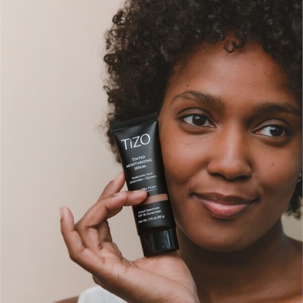 Woman holding luxe black product bottle close to her face
