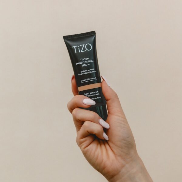 Woman's hand holding luxe black product bottle